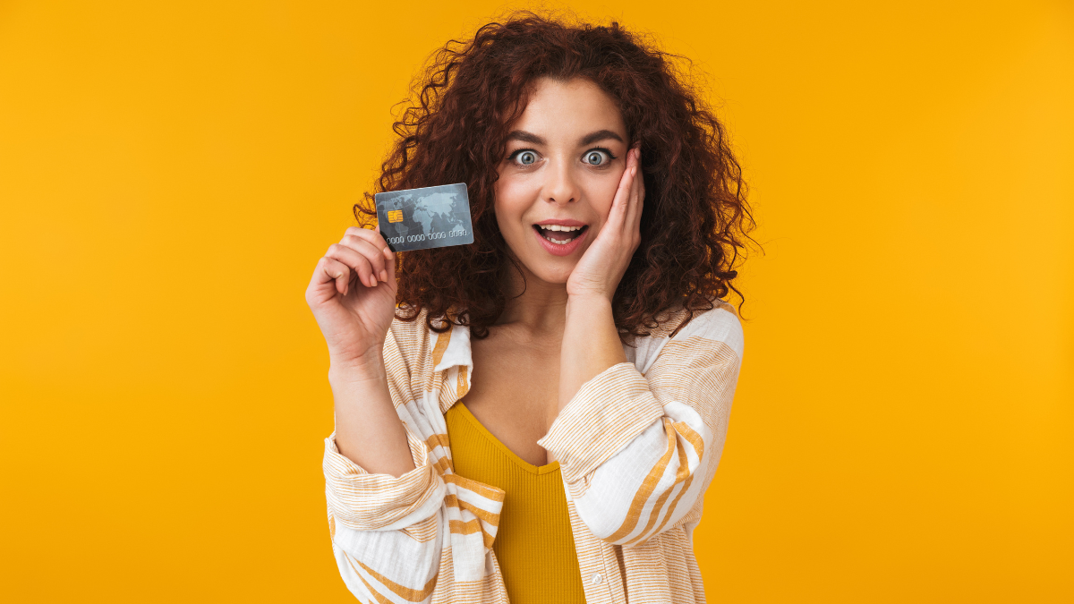 woman holding a credit card on a yellow background